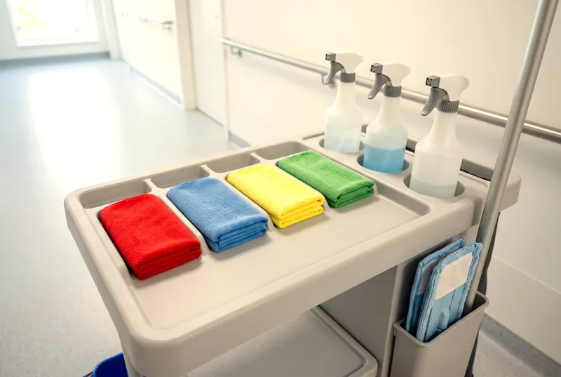 Reinigungswagen im Praxisflur mit Mikrofasertüchern in Rot, Blau, Gelb und Grün